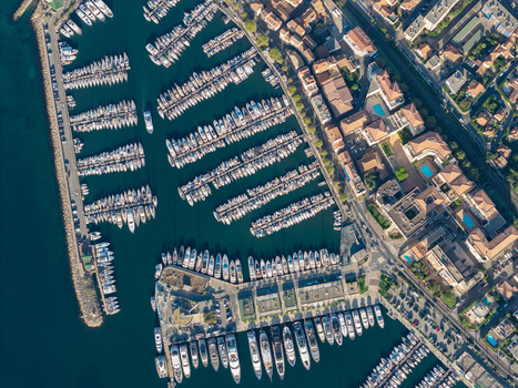 Aerial view of the marina in Antibes filled with numerous yachts and boats docked in rows along the piers with coastal buildings and clear water. Antibes Provence Alpes Cote d Azur France. Aerial view of the marina in Antibes filled with numerous yachts and boats docked in rows along the piers with coastal buildings and clear water. Antibes Provence Alpes Cote d Azur France.