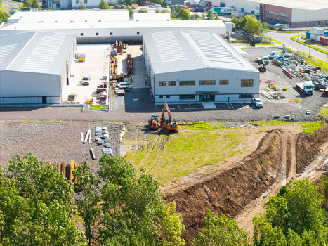 Aerial view of industrial buildings and a construction site with excavators gravel and surrounding trees in Lisburn Northern Ireland United Kingdom. Aerial view of industrial buildings and a construction site with excavators gravel and surrounding trees in Lisburn Northern Ireland United Kingdom.