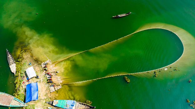 Aerial view of fishermen pulling a large fishing net from a small wooden platform in Kaptai Lake Rangamati Chittagong Division Bangladesh.