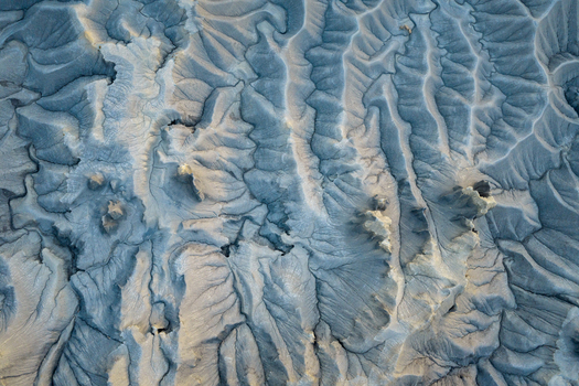 Aerial view of intricate grey bentonite clay formations and eroded badlands with deep gullies and ridges Hanksville Utah United States.