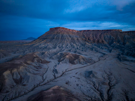 Aerial view of the eroded badlands and desert landscape of Caineville under a dramatic blue hour sky in Caineville Utah United States. Aerial view of the eroded badlands and desert landscape of Caineville under a dramatic blue hour sky in Caineville Utah United States.