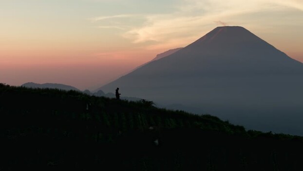 Aerial view of a person overlooking a volcano at sunrise Indonesia.