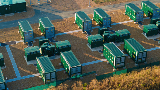 Aerial view of Battery Energy park BESS Grendon featuring rows of green industrial battery storage containers on a gravel site with paved walkways in Northampton England United Kingdom. Aerial view of Battery Energy park BESS Grendon featuring rows of green industrial battery storage containers on a gravel site with paved walkways in Northampton England United Kingdom.