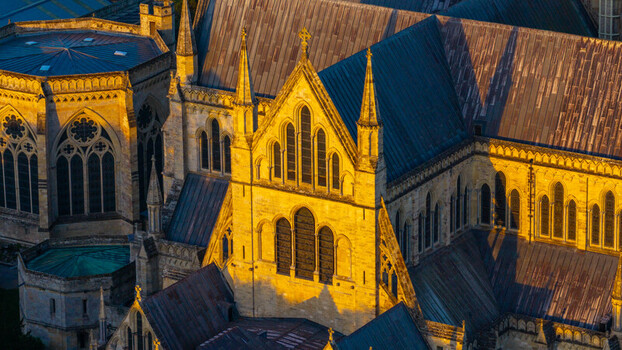 Aerial view of Salisbury Cathedral illuminated by golden hour light showcasing its intricate gothic architecture stone walls and lead roofs in Salisbury England United Kingdom. Aerial view of Salisbury Cathedral illuminated by golden hour light showcasing its intricate gothic architecture stone walls and lead roofs in Salisbury England United Kingdom.