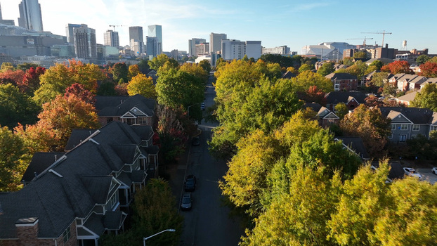 Aerial view of residential housing surrounded by vibrant autumn trees with the downtown Atlanta skyline in the background under a clear blue sky in Atlanta Georgia United States. Aerial view of residential housing surrounded by vibrant autumn trees with the downtown Atlanta skyline in the background under a clear blue sky in Atlanta Georgia United States.