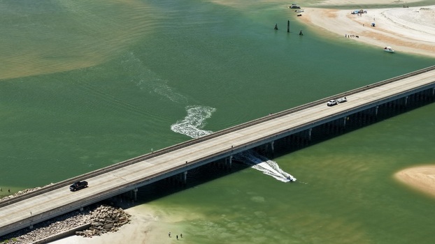 Aerial view of Matanzas Inlet bridge with vehicles crossing over the water and a boat navigating the channel near the sandy shores of St. Johns County Florida United States. Aerial view of Matanzas Inlet bridge with vehicles crossing over the water and a boat navigating the channel near the sandy shores of St. Johns County Florida United States.