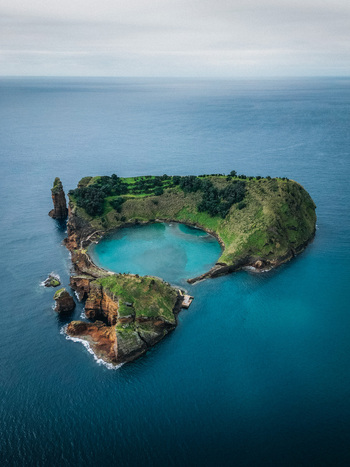 Aerial view of Vila Franca Islet a volcanic crater with a natural pool of turquoise water surrounded by green vegetation Vila Franca do Campo Azores Portugal.