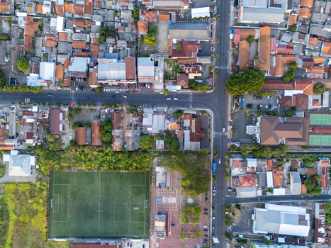 Aerial view of a soccer field situated next to a residential area with dense rooftops and intersecting roads in Cilacap Central Java Indonesia. Aerial view of a soccer field situated next to a residential area with dense rooftops and intersecting roads in Cilacap Central Java Indonesia.