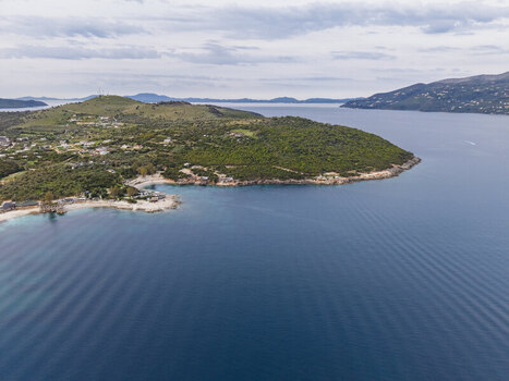 Aerial view of the turquoise waters and rocky coastline with lush green hills and a cloudy sky in the background Ksamil Vlore County Albania. Aerial view of the turquoise waters and rocky coastline with lush green hills and a cloudy sky in the background Ksamil Vlore County Albania.