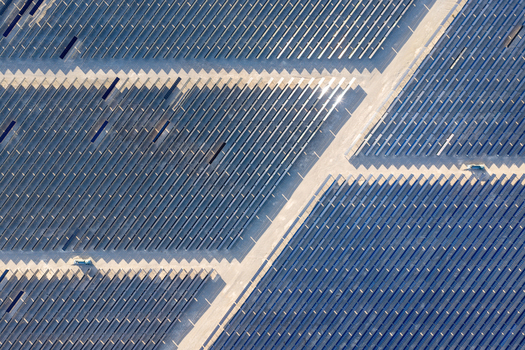 Aerial view of rows of blue solar panels in a geometric pattern across a desert landscape with sunlight reflections in Enterprise Nevada United States. Aerial view of rows of blue solar panels in a geometric pattern across a desert landscape with sunlight reflections in Enterprise Nevada United States.