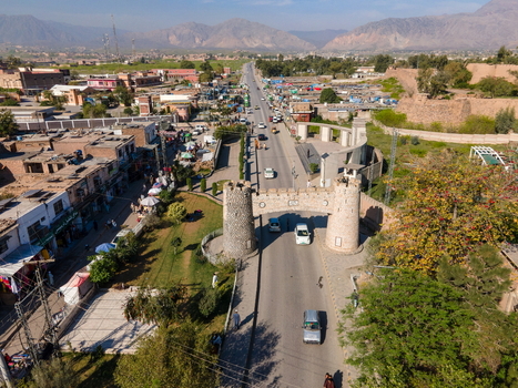 Aerial view of the historic Khyber Pass gate spanning the road with surrounding town buildings mountain landscape and vehicles in Khyber District Khyber Pakhtunkhwa Pakistan. Aerial view of the historic Khyber Pass gate spanning the road with surrounding town buildings mountain landscape and vehicles in Khyber District Khyber Pakhtunkhwa Pakistan.