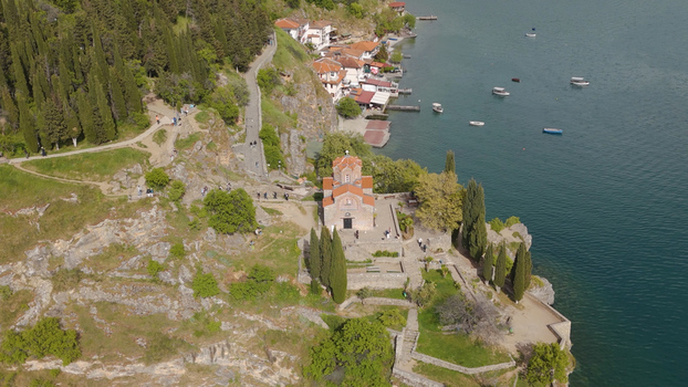 Aerial view of the historic Church of St. John at Kaneo perched on a cliff overlooking Lake Ohrid surrounded by lush greenery and cypress trees in Ohrid North Macedonia. Aerial view of the historic Church of St. John at Kaneo perched on a cliff overlooking Lake Ohrid surrounded by lush greenery and cypress trees in Ohrid North Macedonia.