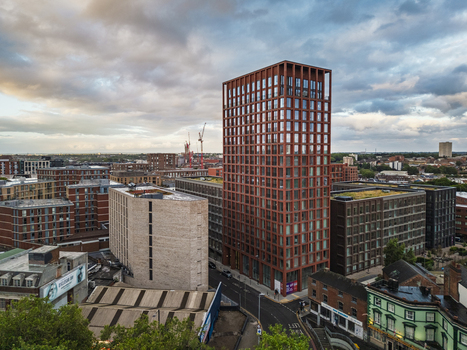 Aerial view of a modern red brick high rise building surrounded by urban architecture streets and rooftops in Birmingham England United Kingdom.