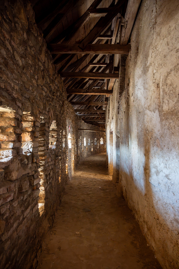 View of the interior corridor of the Prejmer Fortified Church with stone walls wooden roof beams and light filtering through small openings in Prejmer Brasov Romania. View of the interior corridor of the Prejmer Fortified Church with stone walls wooden roof beams and light filtering through small openings in Prejmer Brasov Romania.