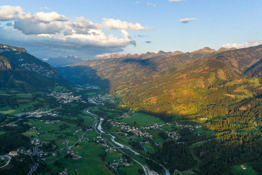 Aerial view of Fiemme Valley with lush green meadows dense pine forests and small mountain villages nestled in the landscape in Trentino Alto Adige Italy.
