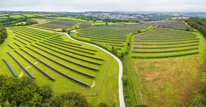 Aerial view of a large solar farm with rows of photovoltaic panels set in green rolling hills and fields in Bodmin Cornwall United Kingdom. Aerial view of a large solar farm with rows of photovoltaic panels set in green rolling hills and fields in Bodmin Cornwall United Kingdom.