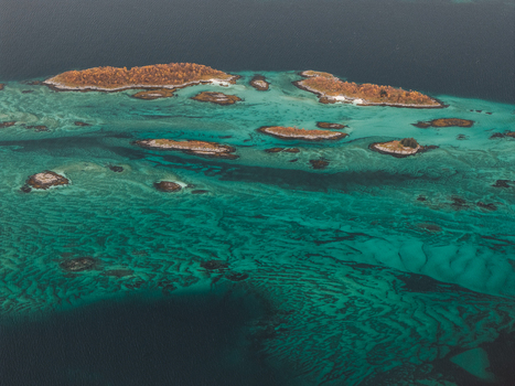 Aerial view of the turquoise waters and rocky islets of Senja with autumn foliage in Senja Troms Norway.
