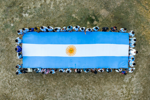 Bogura Bangladesh 02 December 2022 Aerial view of a large group of people holding a massive Argentine flag in a field.