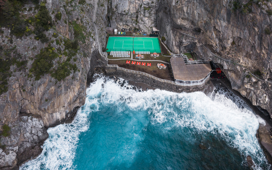 Aerial view of jagged cliffs embrace a vibrant green tennis court nestled beside the turquoise sea 2 Via Laurito Laurito Campania Italy. Aerial view of jagged cliffs embrace a vibrant green tennis court nestled beside the turquoise sea 2 Via Laurito Laurito Campania Italy.