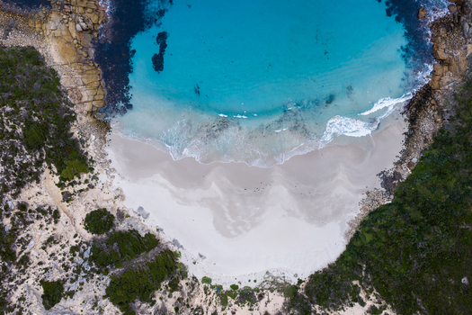 Aerial view of Jimmy Newells Harbour featuring turquoise waters white sand beach and surrounding rocky coastline with lush vegetation in Albany WA Australia. Aerial view of Jimmy Newells Harbour featuring turquoise waters white sand beach and surrounding rocky coastline with lush vegetation in Albany WA Australia.