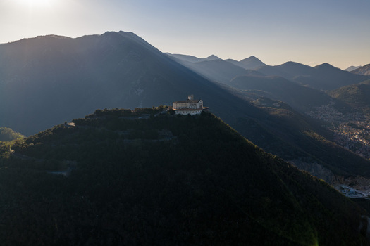 Aerial view of Santuario del Santissimo Salvatore on a mountain peak surrounded by lush forests and hazy peaks during sunset Montella Campania Italy. Aerial view of Santuario del Santissimo Salvatore on a mountain peak surrounded by lush forests and hazy peaks during sunset Montella Campania Italy.