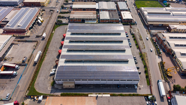 Aerial view of a transport company facility featuring extensive rooftop solar panels surrounded by industrial warehouses and roads in Milan Lombardy Italy.