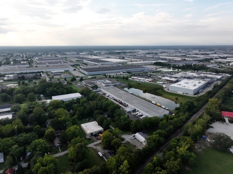 Aerial view of industrial warehouses and logistics facilities surrounded by green trees and a small pond in Indianapolis Indiana United States. Aerial view of industrial warehouses and logistics facilities surrounded by green trees and a small pond in Indianapolis Indiana United States.