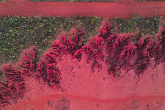 Aerial view of the vibrant red earth landscape featuring intricate erosion patterns sparse desert vegetation and dusty tracks in Broome Western Australia Australia.