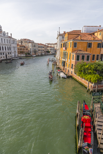 Venice Italy 21 September 2026 View of the Grand Canal with a traditional gondola moored at a wooden pier historic orange buildings and boats navigating the waterway. Venice Italy 21 September 2026 View of the Grand Canal with a traditional gondola moored at a wooden pier historic orange buildings and boats navigating the waterway.