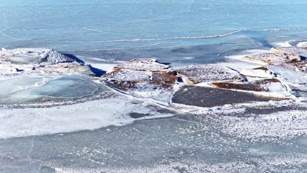 Aerial view of ice floes and frozen water surface with cracked patterns and snow covered textures in Latvija. Aerial view of ice floes and frozen water surface with cracked patterns and snow covered textures in Latvija.