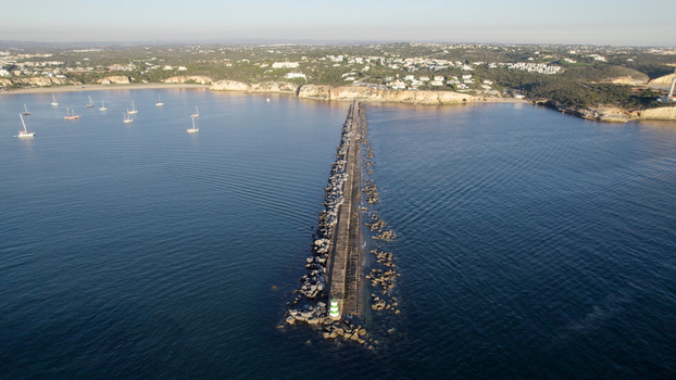 Aerial view of the breakwater and lighthouse at Ferragudo with boats in the bay and coastal cliffs in the background Ferragudo Faro District Portugal.
