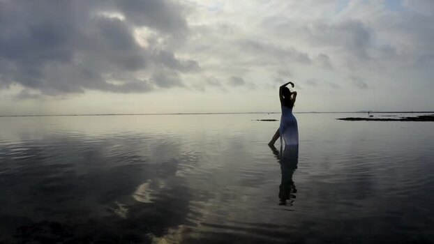 Aerial view of a woman in a white dress in calm water Indonesia.