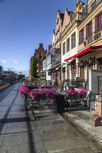 Gdansk Poland 06 September 2026 View of an outdoor restaurant terrace with vibrant pink flowers in planters set against historic architecture along the waterfront. Gdansk Poland 06 September 2026 View of an outdoor restaurant terrace with vibrant pink flowers in planters set against historic architecture along the waterfront.