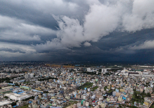 Chattogram Bangladesh 22 September 2026 Aerial view of the dense urban cityscape with residential buildings and port infrastructure under a dramatic dark storm filled sky.