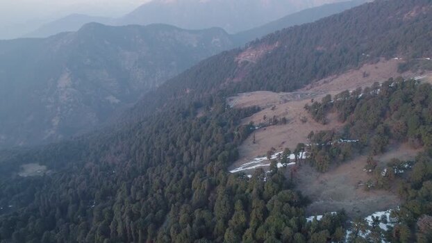 Aerial view of forested mountains and snow in Chopta India.
