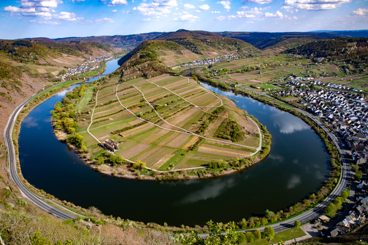 Aerial view of the Moselle River loop at Bremm featuring terraced vineyards on steep hillsides a winding river and a village along the banks. Bremm Rhineland Palatinate Germany. Aerial view of the Moselle River loop at Bremm featuring terraced vineyards on steep hillsides a winding river and a village along the banks. Bremm Rhineland Palatinate Germany.