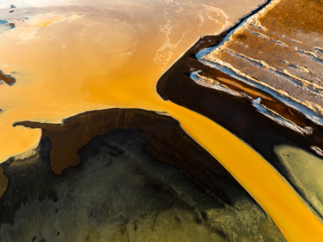 Aerial view of the volcanic landscape showing contrasting textures of dark basaltic sand and vibrant yellow mineral rich water flowing through the terrain Reykjanesbaer Iceland. Aerial view of the volcanic landscape showing contrasting textures of dark basaltic sand and vibrant yellow mineral rich water flowing through the terrain Reykjanesbaer Iceland.