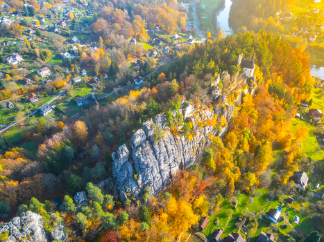 Aerial view of the ruin of the rock castle Vranov perched on a rocky ridge surrounded by vibrant autumn forests and a winding river in Mala Skala Liberecky kraj Czechia. Aerial view of the ruin of the rock castle Vranov perched on a rocky ridge surrounded by vibrant autumn forests and a winding river in Mala Skala Liberecky kraj Czechia.