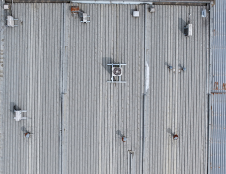 Aerial view of a corrugated metal industrial roof featuring various HVAC units ventilation systems and structural seams in Melbourne VIC Australia.