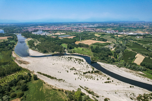 Aerial view of the Po River showing severe drought conditions with exposed riverbed surrounded by agricultural fields and greenery Chivasso Piedmont Italy.