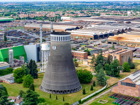 Aerial view of the TenarisDalmine industrial plant cooling tower and factory buildings surrounded by green trees in Dalmine Lombardy Italy. Aerial view of the TenarisDalmine industrial plant cooling tower and factory buildings surrounded by green trees in Dalmine Lombardy Italy.