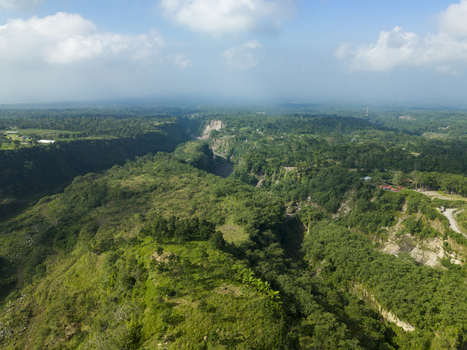 Aerial view of Tambang Pasir Merapi Kali Gendol Sand Mine with lush green tropical vegetation and steep canyon walls in Kecamatan Cangkringan Daerah Istimewa Yogya Indonesia. Aerial view of Tambang Pasir Merapi Kali Gendol Sand Mine with lush green tropical vegetation and steep canyon walls in Kecamatan Cangkringan Daerah Istimewa Yogya Indonesia.