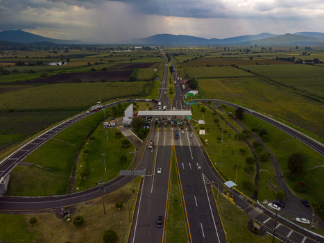 Aerial view of the Autopista Mexico Guadalajara toll booth surrounded by agricultural fields and rolling hills under a dramatic cloudy sky in Ecuandureo Michoacan Mexico. Aerial view of the Autopista Mexico Guadalajara toll booth surrounded by agricultural fields and rolling hills under a dramatic cloudy sky in Ecuandureo Michoacan Mexico.