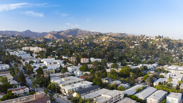 Aerial view of residential neighborhoods in the Hollywood Hills featuring dense houses lush trees and the Santa Monica Mountains in Los Angeles California United States.