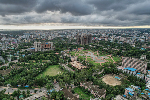Chattogram Bangladesh 22 June 2022 Aerial view of the urban landscape featuring a central park with ponds dense buildings lush green trees and a dramatic cloudy sky.