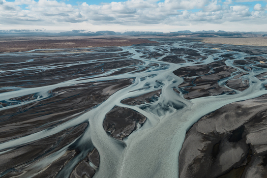Aerial view of the intricate braided river system flowing through the dark volcanic landscape of Skaftarhreppur Iceland.