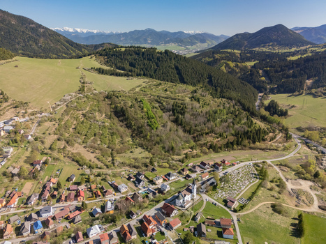 Aerial view of the village of Valaska Dubova with its church and cemetery surrounded by lush green hills and distant snow capped mountains Valaska Dubova Zilina Region Slovakia. Aerial view of the village of Valaska Dubova with its church and cemetery surrounded by lush green hills and distant snow capped mountains Valaska Dubova Zilina Region Slovakia.