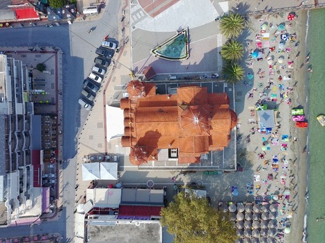 Aerial view of the Church of Agia Fotini with its red tiled roof surrounded by a sandy beach with umbrellas nearby buildings and a parking area in Paralia Katerinis Pieria Greece. Aerial view of the Church of Agia Fotini with its red tiled roof surrounded by a sandy beach with umbrellas nearby buildings and a parking area in Paralia Katerinis Pieria Greece.