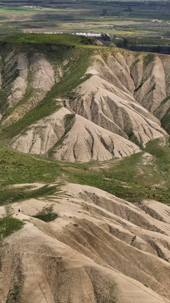 Aerial view of the rugged landscape reveals a tapestry of earthy tones where barren peaks meet verdant valleys under a vast sky Centuripe Sicilia Italy. Aerial view of the rugged landscape reveals a tapestry of earthy tones where barren peaks meet verdant valleys under a vast sky Centuripe Sicilia Italy.