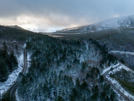 Aerial view of winding roads through snow covered pine forests in the Serra da Estrela mountains under a misty winter sky Unhais da Serra Castelo Branco District Portugal. Aerial view of winding roads through snow covered pine forests in the Serra da Estrela mountains under a misty winter sky Unhais da Serra Castelo Branco District Portugal.